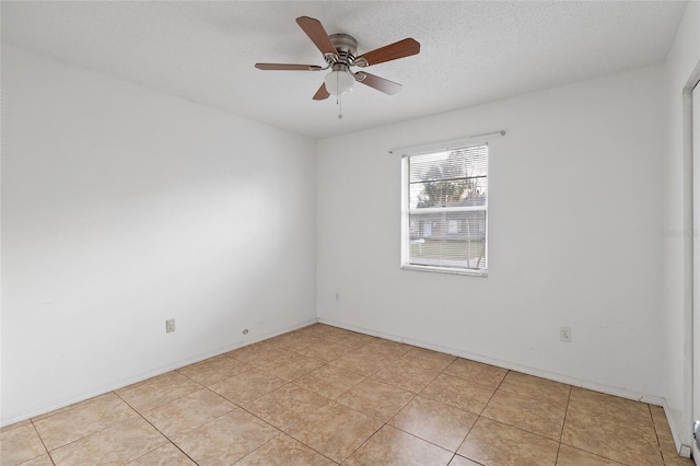 spare room featuring ceiling fan, light tile patterned floors, and a textured ceiling