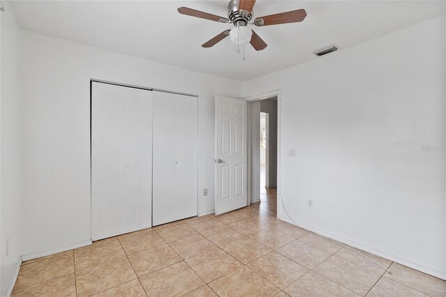 unfurnished bedroom featuring light tile patterned flooring, ceiling fan, and a closet