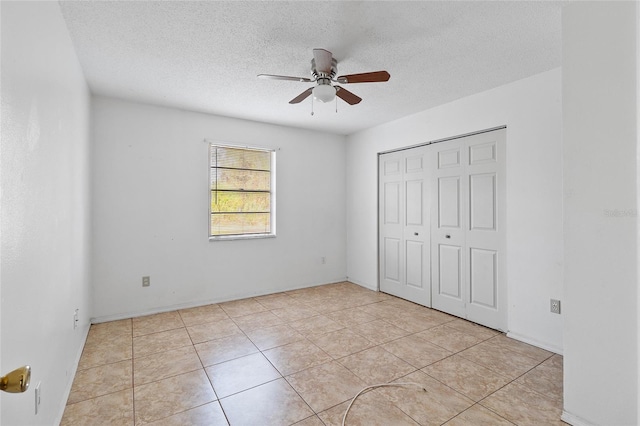 unfurnished bedroom featuring ceiling fan, light tile patterned flooring, a textured ceiling, and a closet