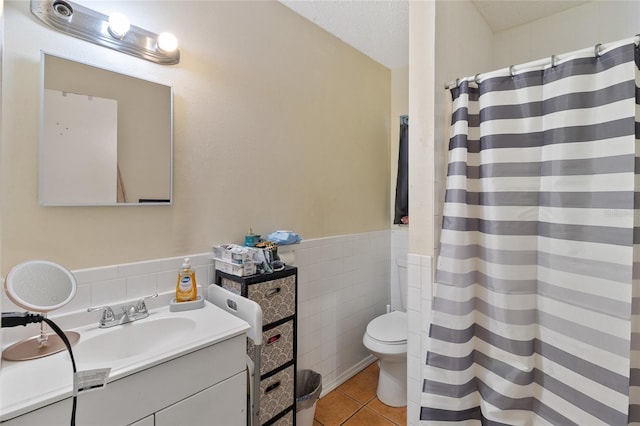 bathroom with toilet, tile walls, a textured ceiling, vanity, and tile patterned flooring