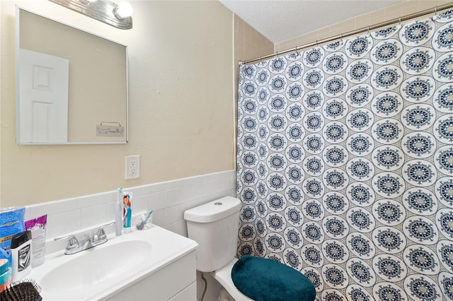 bathroom with tile walls, vanity, toilet, a textured ceiling, and a shower with shower curtain