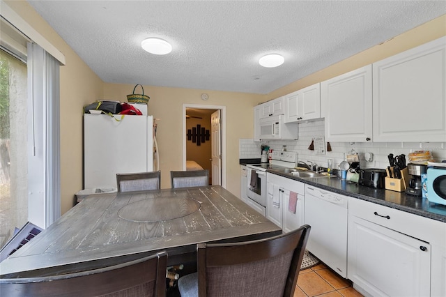 kitchen featuring light tile patterned flooring, sink, white cabinetry, white appliances, and decorative backsplash