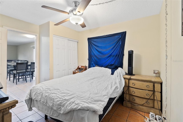 bedroom featuring ceiling fan, a textured ceiling, a closet, and light tile patterned floors