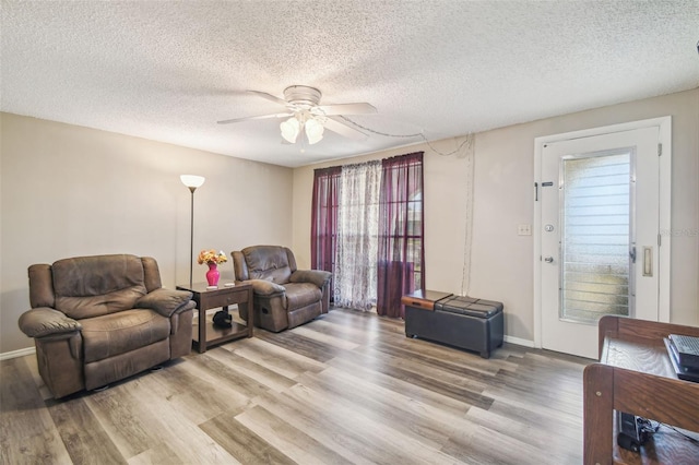 living room with light hardwood / wood-style floors, a textured ceiling, and ceiling fan