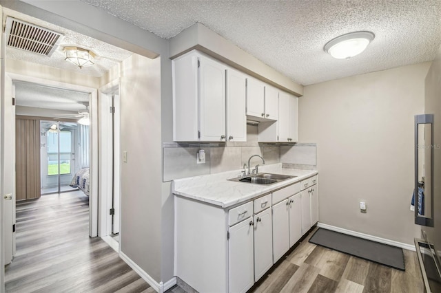 kitchen featuring sink, white cabinets, a textured ceiling, light hardwood / wood-style floors, and ceiling fan