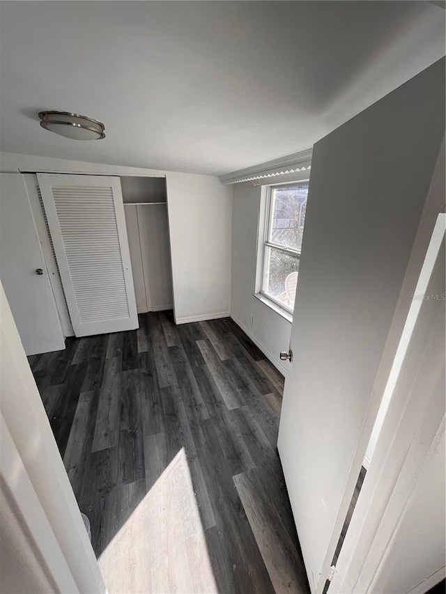 unfurnished bedroom with a closet and dark wood-type flooring