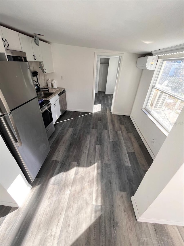 kitchen featuring white cabinets, appliances with stainless steel finishes, dark hardwood / wood-style flooring, and an AC wall unit