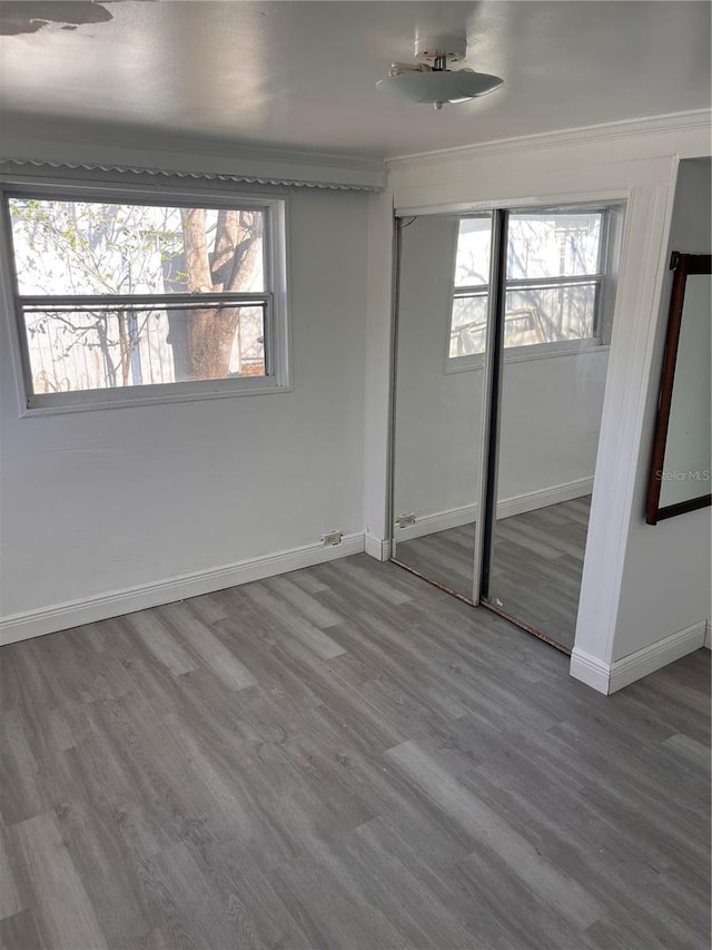 unfurnished bedroom with hardwood / wood-style flooring, ornamental molding, and a closet