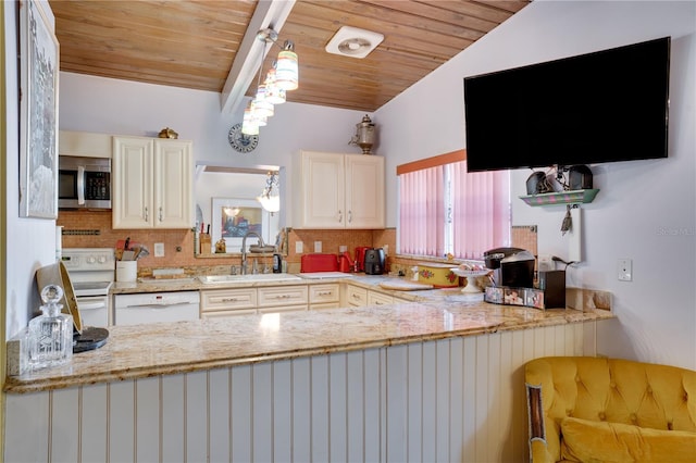 kitchen featuring lofted ceiling, white appliances, sink, hanging light fixtures, and light stone countertops