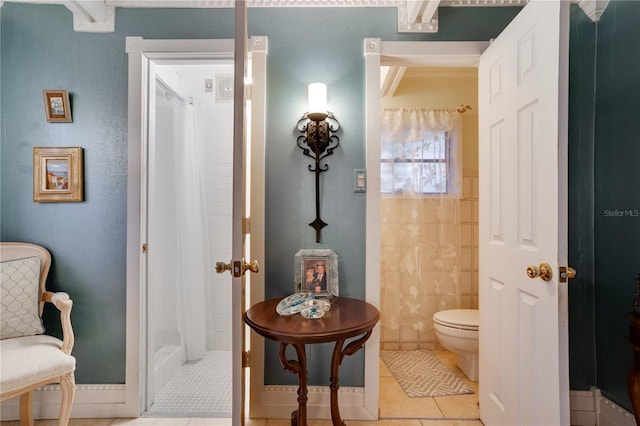 bathroom with tiled shower, tile patterned floors, and toilet