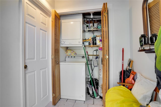 clothes washing area featuring light tile patterned floors and stacked washer and dryer