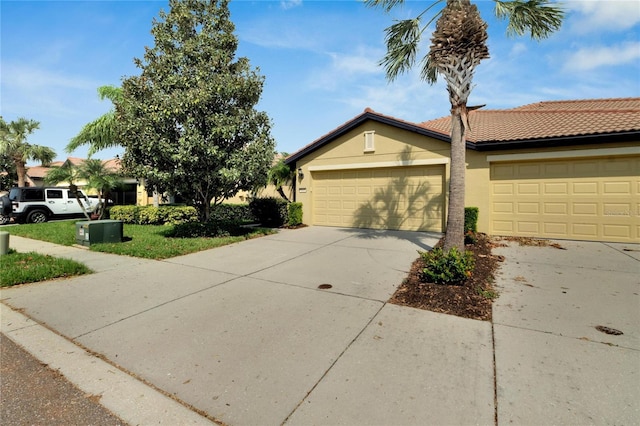 view of property with an attached garage, a tiled roof, driveway, and stucco siding