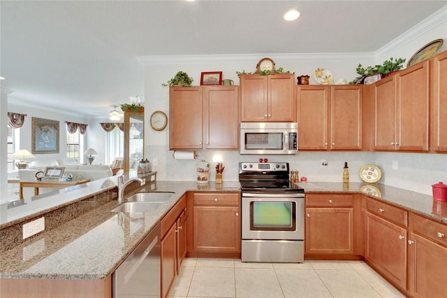 kitchen with light stone countertops, appliances with stainless steel finishes, kitchen peninsula, crown molding, and sink