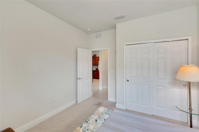 unfurnished bedroom with a closet, visible vents, light colored carpet, and baseboards