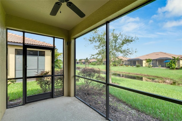 unfurnished sunroom with ceiling fan and a residential view