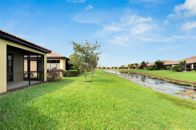 view of yard with a sunroom and a water view