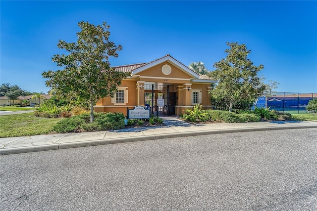 bungalow-style home with stucco siding, fence, a tile roof, and a gate