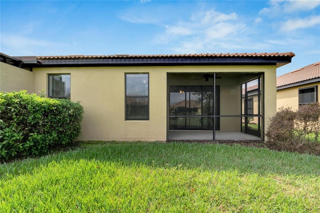 rear view of property featuring a lawn, ceiling fan, and a sunroom