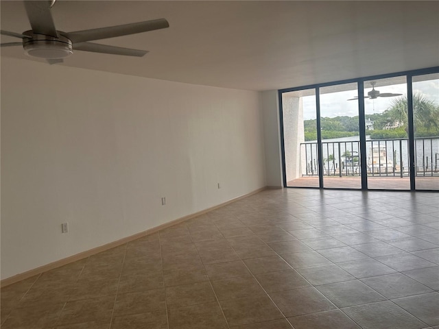 tiled empty room featuring a water view and ceiling fan