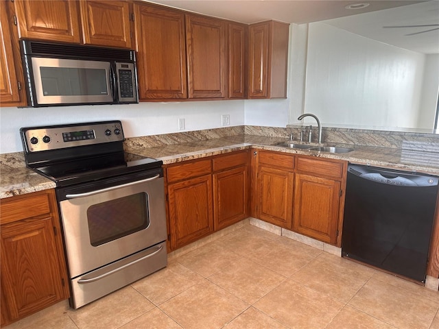 kitchen featuring light stone countertops, light tile patterned floors, appliances with stainless steel finishes, and sink