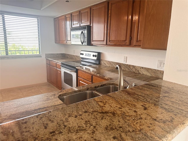 kitchen with kitchen peninsula, sink, stainless steel range with electric stovetop, and light tile patterned floors