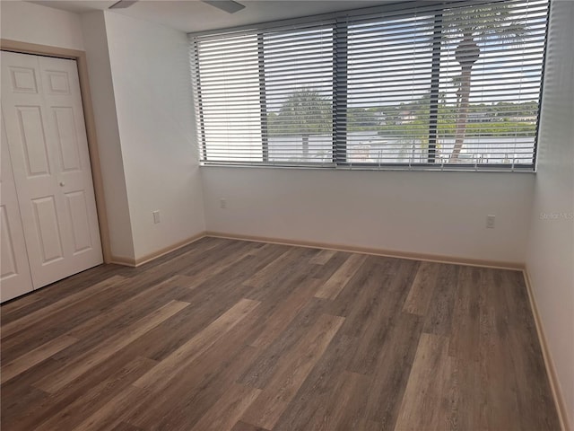 unfurnished bedroom with a closet, multiple windows, and dark hardwood / wood-style flooring