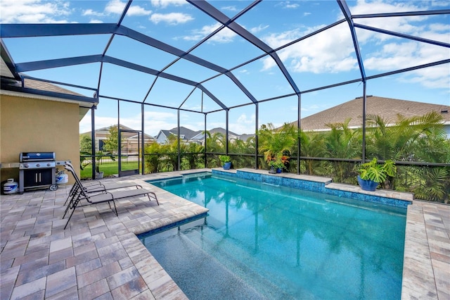 view of pool with a grill, a patio area, and glass enclosure