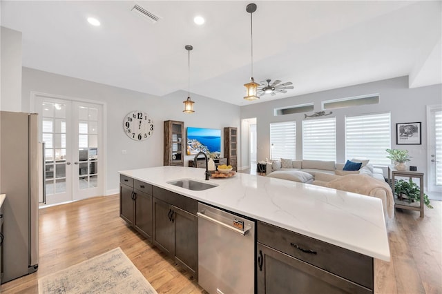 kitchen with pendant lighting, sink, appliances with stainless steel finishes, an island with sink, and french doors