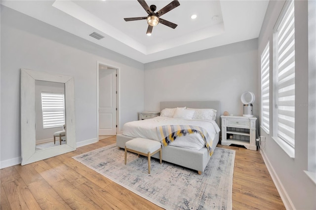 bedroom featuring ceiling fan, a tray ceiling, and hardwood / wood-style floors