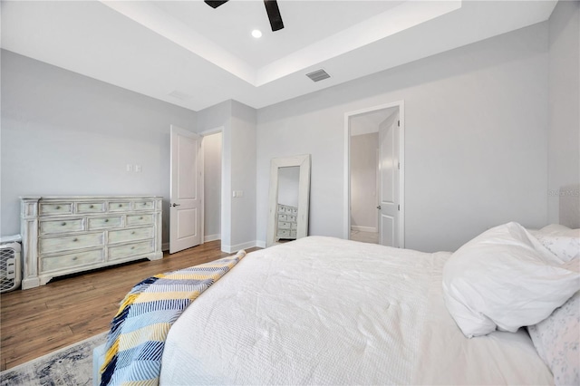 bedroom featuring hardwood / wood-style flooring, ceiling fan, and a tray ceiling