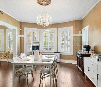 dining space with a notable chandelier, a textured ceiling, a wealth of natural light, and dark hardwood / wood-style floors