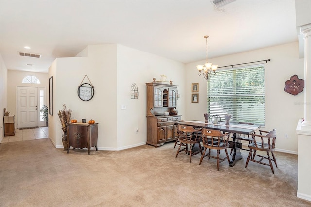 carpeted dining room featuring a notable chandelier and ornate columns