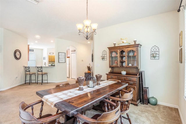 carpeted dining area with an inviting chandelier