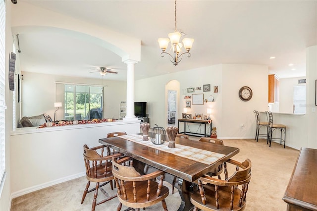 dining space with ceiling fan with notable chandelier, ornate columns, and light carpet