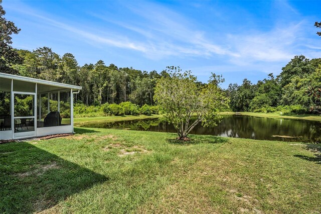 view of yard with a sunroom and a water view