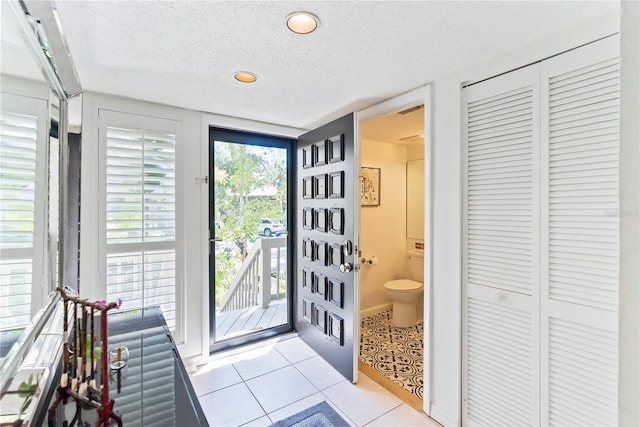 doorway featuring light tile patterned floors and a textured ceiling