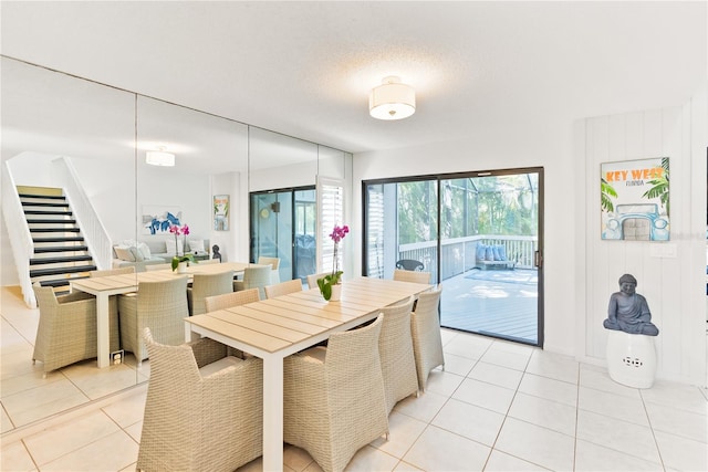 dining room featuring light tile patterned floors, stairway, and a textured ceiling