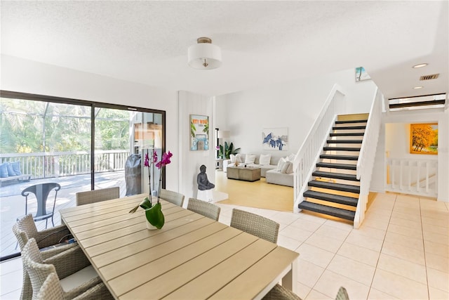 dining space with stairs, visible vents, a textured ceiling, and light tile patterned floors