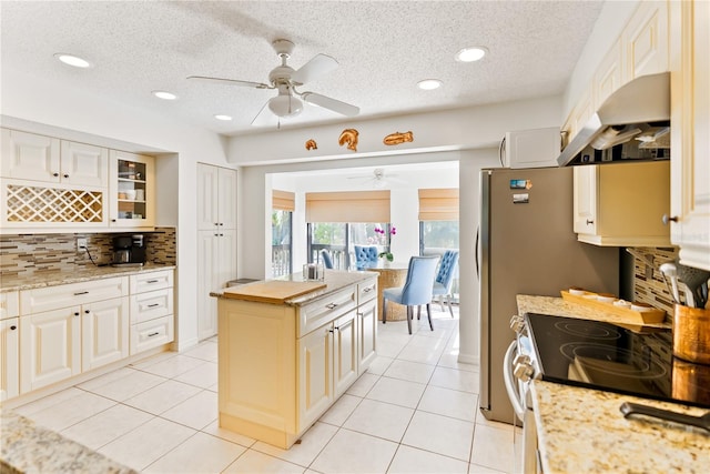 kitchen featuring tasteful backsplash, electric stove, under cabinet range hood, and light tile patterned floors