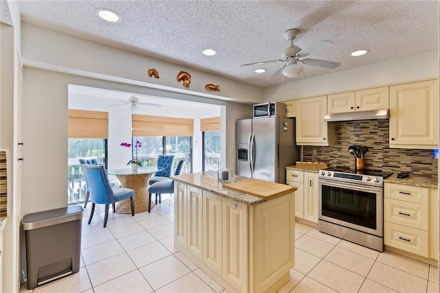 kitchen with appliances with stainless steel finishes, cream cabinetry, ceiling fan, and tasteful backsplash