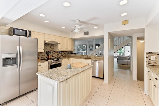 kitchen featuring light tile patterned floors, under cabinet range hood, stainless steel appliances, a sink, and visible vents