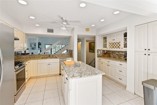 kitchen with appliances with stainless steel finishes, a center island, visible vents, and light tile patterned floors