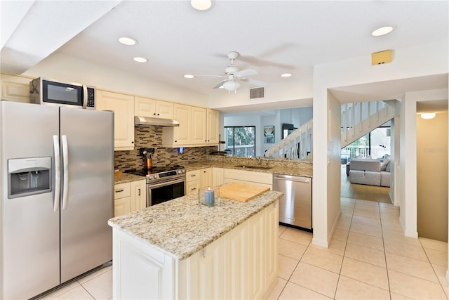 kitchen with ceiling fan, sink, light stone counters, light tile patterned floors, and appliances with stainless steel finishes