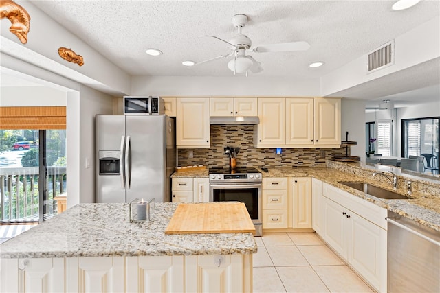 kitchen featuring visible vents, appliances with stainless steel finishes, under cabinet range hood, a sink, and light tile patterned flooring