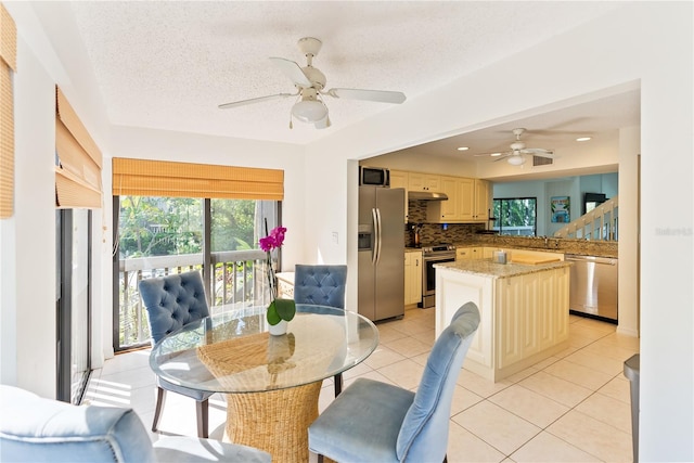 tiled dining area featuring ceiling fan and a textured ceiling