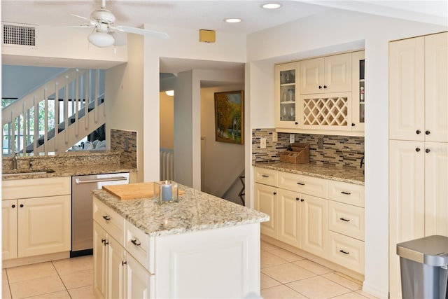 kitchen featuring light stone countertops, dishwasher, a center island, and light tile patterned floors