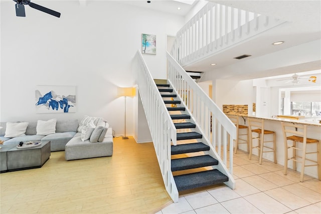 stairway with ceiling fan, recessed lighting, wood finished floors, visible vents, and a towering ceiling