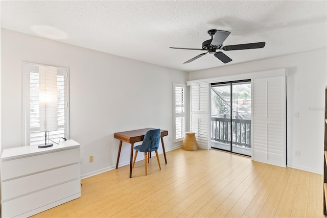 interior space featuring a textured ceiling, ceiling fan, light wood finished floors, and baseboards