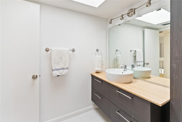 bathroom with tile patterned flooring, a skylight, visible vents, vanity, and baseboards