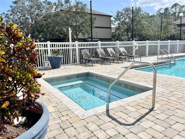 view of swimming pool featuring a patio area and an in ground hot tub